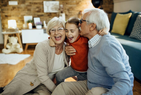 Cheerful grandparents and granddaughter having fun together at h