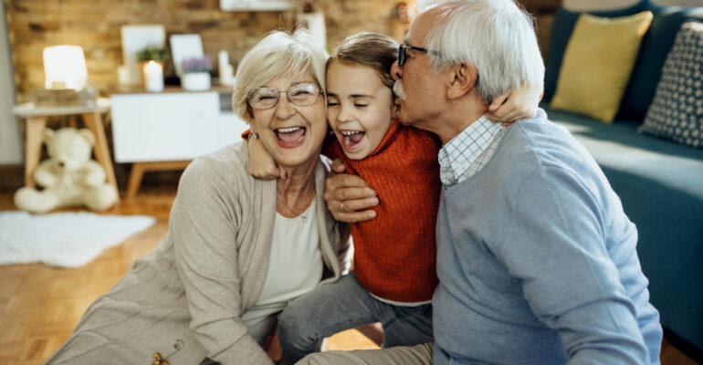 Cheerful grandparents and granddaughter having fun together at h